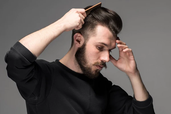 man styling his hair with a comb