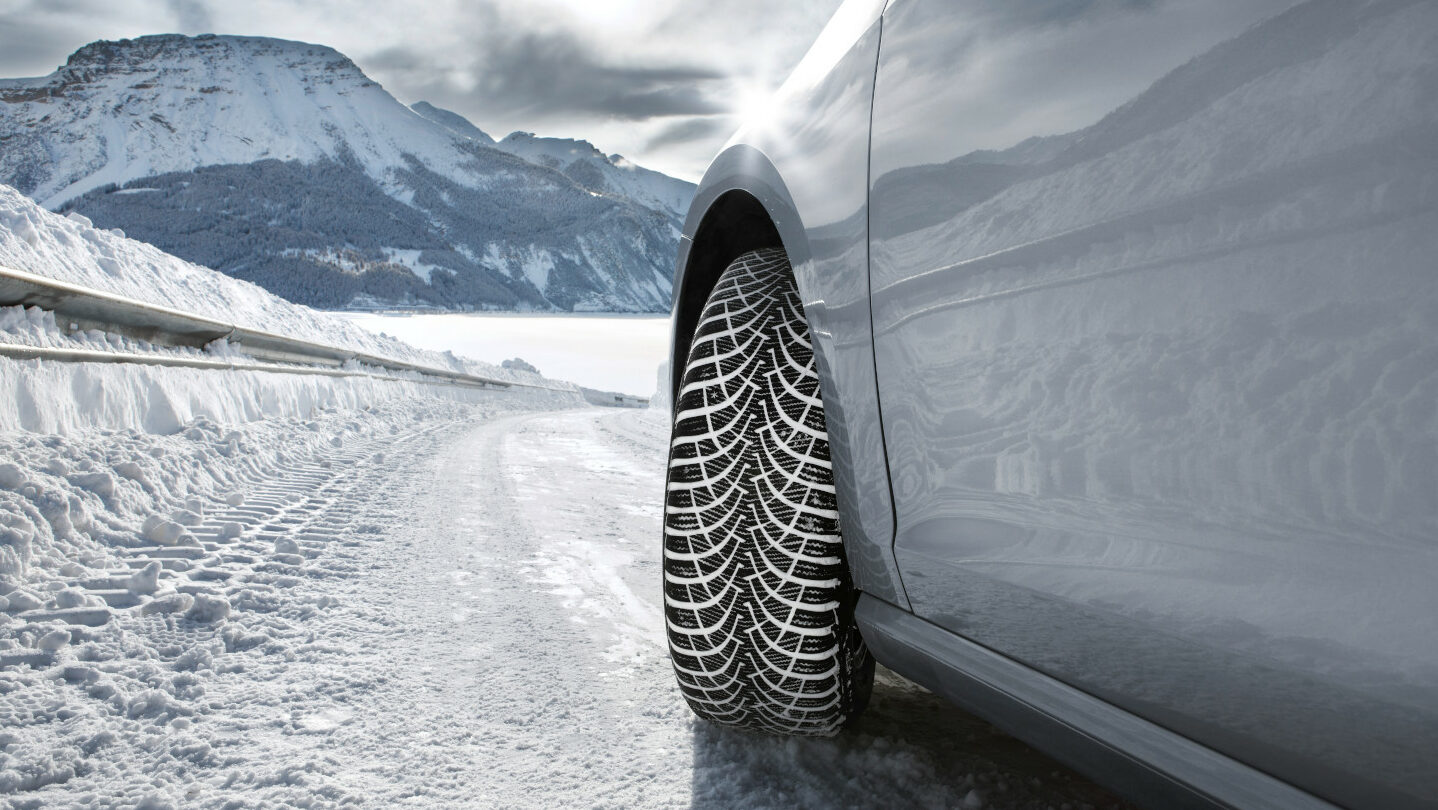 winter tyre on snow with mountains in the background