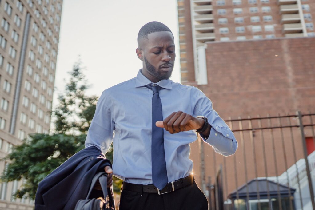 Black male in smart suit checking the time