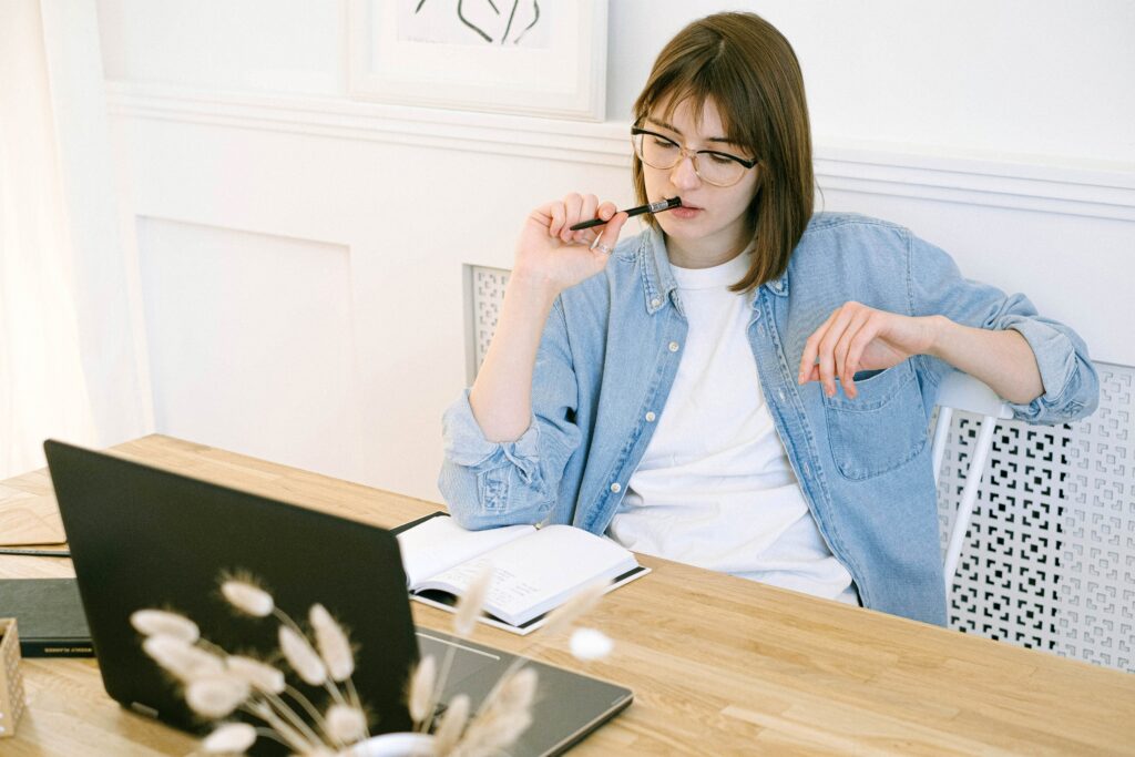 Female thinking about her finances with a laptop and notebook